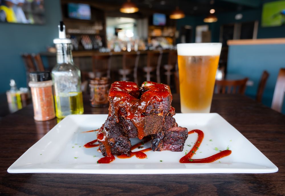 Slow-smoked BBQ ribs drizzled with house-made sauce, served with a beer